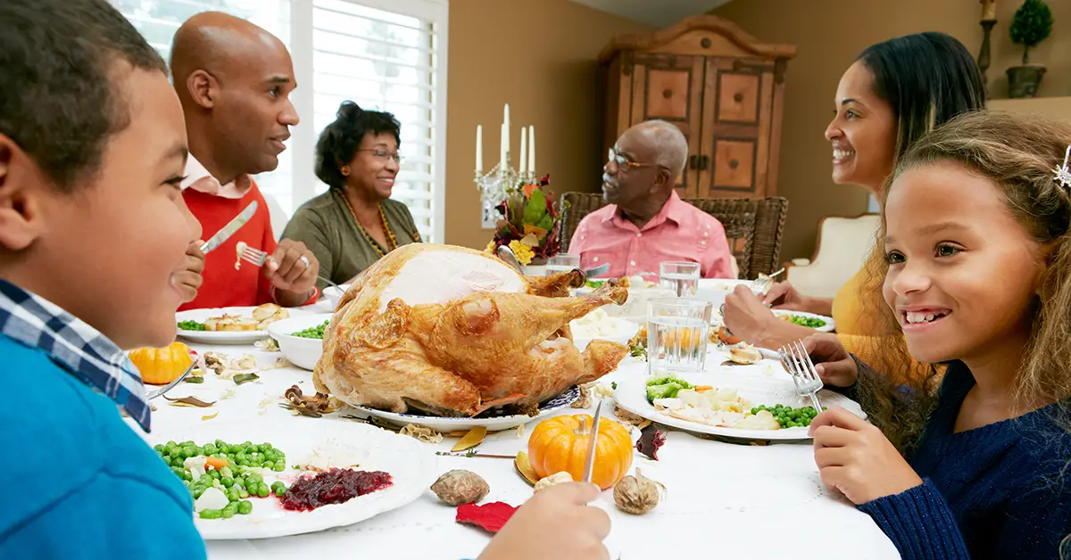 Photo of multi-generational family talking over Thanksgiving dinner - Photo by Adobe Stock