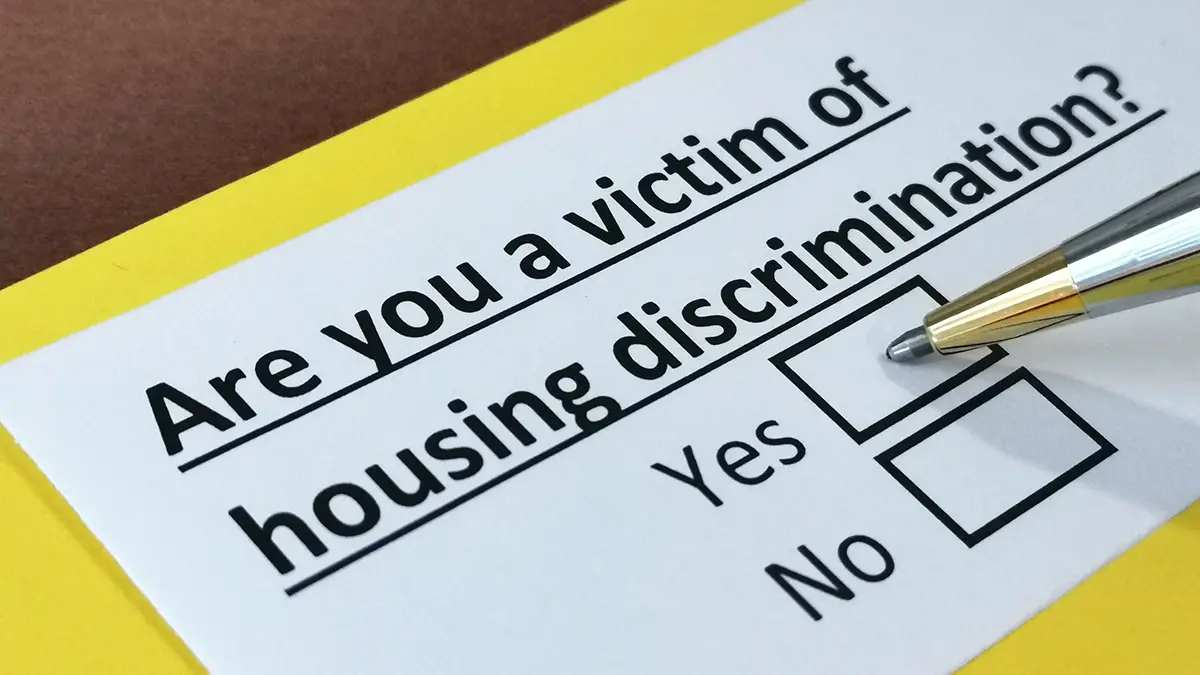 Photo of a form that asks "Are you a victim of housing discrimination?" with a pen hovering over the "Yes" option. Photo By Richelle - Adobe Stock